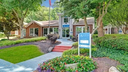 Community leasing office surrounded by landscaped greenery and flowers.
