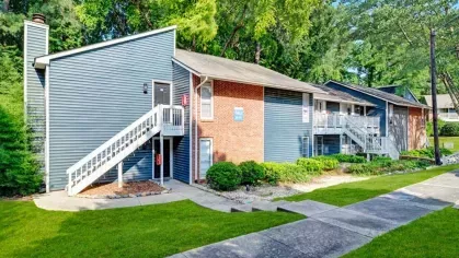 Apartment building with a mix of brick and blue paneling, and landscaping.