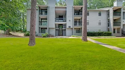 Contemporary apartment building with balconies and a neatly manicured lawn.