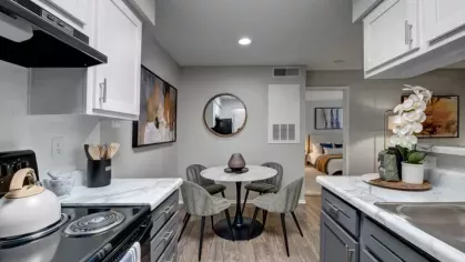 A cozy kitchen and dining area with white cabinets, marble countertops, and a round dining table.