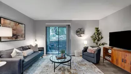 A contemporary living room with a sliding door to a balcony and stylish decor.