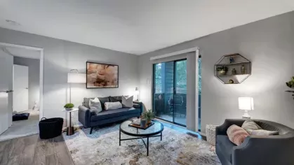 A cozy living room with modern furniture and a large sliding glass door leading to a balcony.