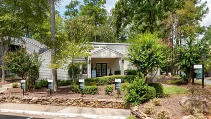 Leasing office entrance surrounded by vibrant landscaping and signage.