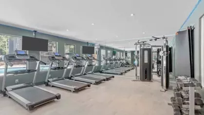 A spacious fitness center with multiple treadmills, weight equipment, and wall-length mirrors.