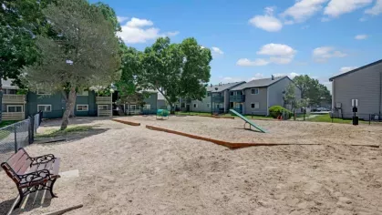 Spacious outdoor dog park featuring open play areas, walking paths, and shaded seating, surrounded by apartment buildings and lush greenery, providing a fun space for pets and their owners.
