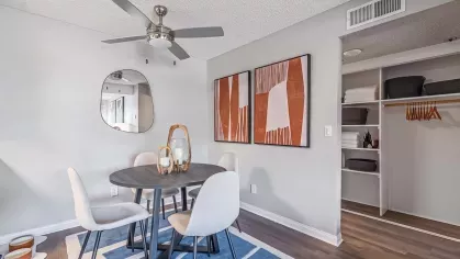 Contemporary dining area with a round table, modern white chairs, abstract wall art, and an open closet for storage.