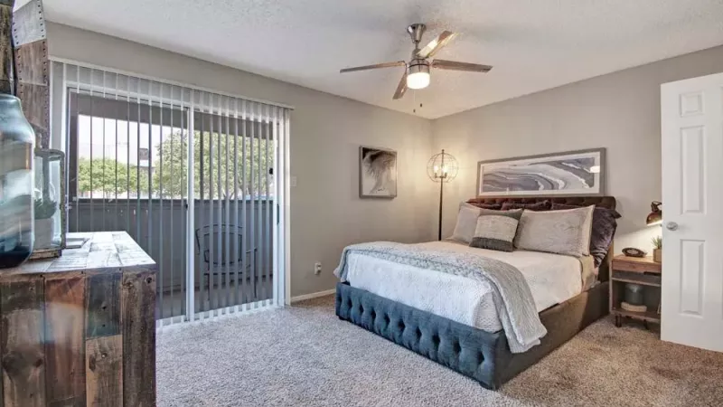 Spacious bedroom featuring a ceiling fan, plush carpeting, and access to a private balcony.