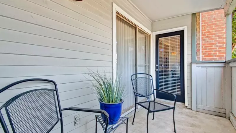 Outdoor balcony with comfortable seating and a blue potted plant.