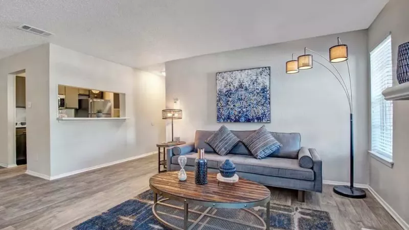 Modern living room with a gray couch, abstract wall art, and a stylish floor lamp.