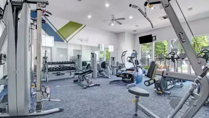 Fully equipped fitness center featuring a variety of modern exercise machines, free weights, and bright natural lighting. The spacious and well-designed layout creates an inviting atmosphere for an effective workout experience.