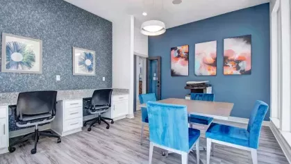 Stylish community workspace with comfortable seating, a sleek design, and vibrant blue decor. The area features desks, computers, and modern art, providing an ideal environment for productivity and collaboration.