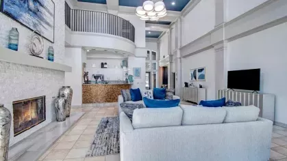 Elegant resident lounge with high ceilings, a cozy fireplace, and contemporary furnishings in soothing tones. The open layout includes a luxurious seating area and sophisticated decor for a comfortable gathering space.