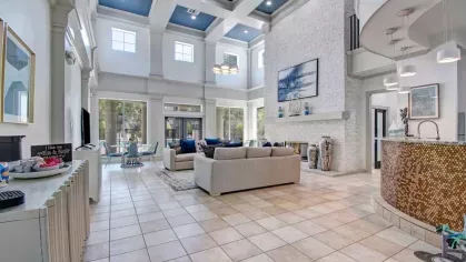 Expansive resident clubhouse with a stunning two-story design, featuring a stylish seating area, modern kitchen, and floor-to-ceiling windows that flood the space with natural light. The grand fireplace and chic decor add a touch of luxury.