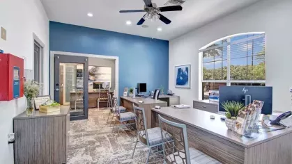 Welcoming leasing office with a modern design and professional layout, featuring large windows, sleek desks, and comfortable chairs. The bright and inviting space is perfect for prospective residents and community services.