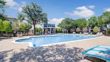 Large community pool surrounded by scenic landscaping, modern lounge chairs, and shaded seating areas. The perfect spot to unwind and enjoy the outdoors in a tranquil setting.