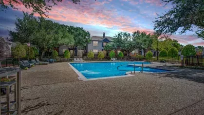 Stunning community pool captured at sunset, with vibrant skies reflecting on the water. The well-lit space offers a serene evening ambiance for relaxation or a refreshing swim.