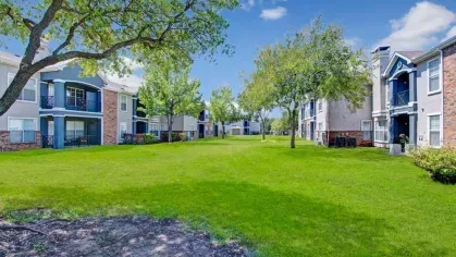 Expansive green space within the community, surrounded by well-maintained apartment buildings and mature trees, offering a peaceful environment for relaxation and recreation.