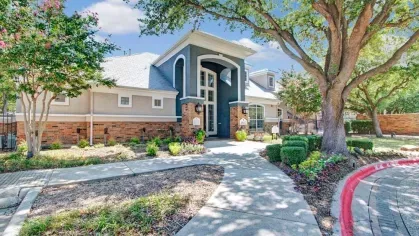 Beautiful leasing office with a modern architectural design, surrounded by vibrant landscaping and mature trees. A welcoming entrance path adds charm to the community’s main office area.