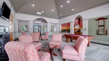 A recreational room with comfortable chairs, a pool table, and a TV.