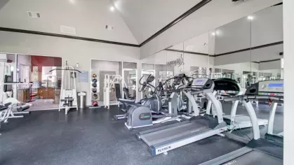 A spacious fitness center with treadmills, weight machines, and wall mirrors.