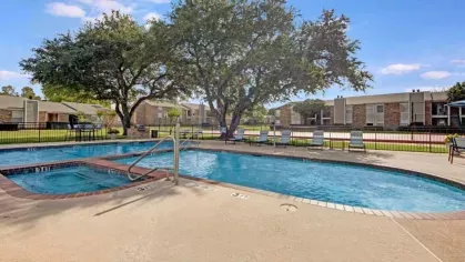 A serene pool area with a tree-lined backdrop and comfortable seating options on the deck.
