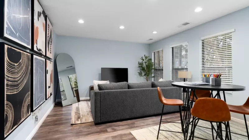 A stylish lounge area with modern decor, a gray sectional sofa, and a small dining setup for casual meetings or relaxation.
