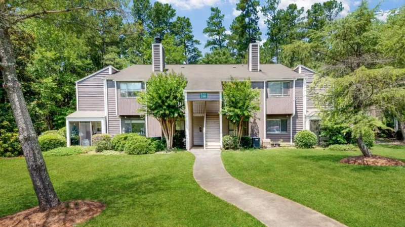 A bright, inviting apartment complex with a tree-lined pathway and well-maintained landscaping.