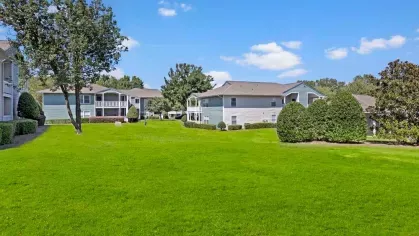 Expansive grassy lawn surrounded by apartment buildings and manicured bushes.