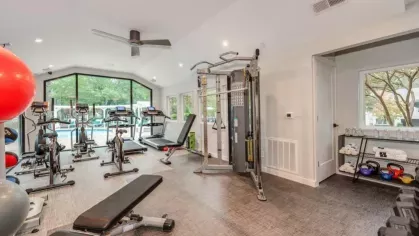 Another angle of the fitness center showcasing a variety of workout equipment and a view of the pool outside.