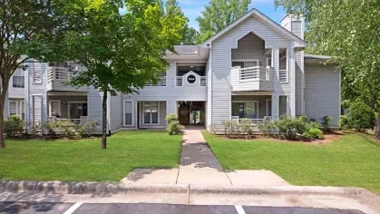 A front-facing view of modern, gray two-story apartments with well-maintained landscaping.