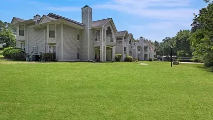 Spacious green lawns stretching in front of two-story gray apartments.