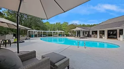 A stylish poolside view with shaded seating and a community clubhouse.