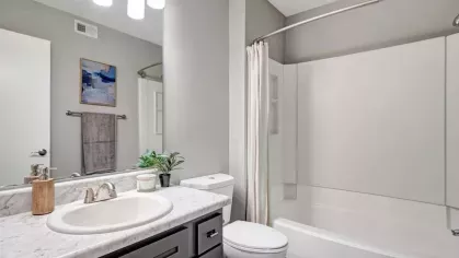 A modern bathroom featuring a sleek marble countertop and a white bathtub with neutral decor accents.