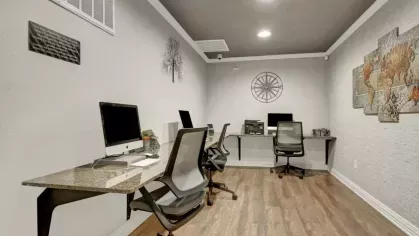 A modern business center featuring computer workstations, ergonomic chairs, and a clean layout.