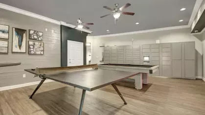 A spacious game room with ample seating and entertainment facilities including a ping pong table and lockers.