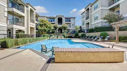 Pool area with water features and ample seating, framed by elegant apartment buildings and manicured landscaping.