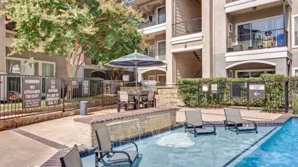 View of the pool featuring shaded seating, water features, and a modern apartment setting.