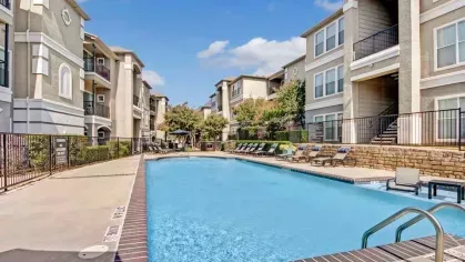 Elegant pool deck showcasing a clean and serene apartment community with sunbathing and dining areas.