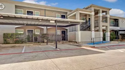 Residential building with covered parking and a wheelchair-accessible ramp leading to the entrance.