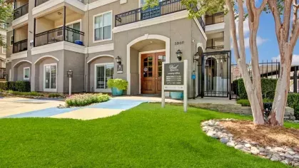 Leasing office entrance surrounded by well-maintained green grass and colorful landscaping.