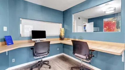 A cozy business center with two workstations, a desktop computer, and blue accent walls, creating a productive work environment.