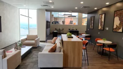 A modern clubhouse lounge with a cozy seating area and large windows offering city views.