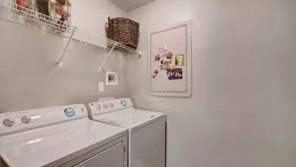 A dedicated laundry room equipped with a washer, dryer, and a shelf for storage.
