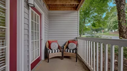 A charming outdoor patio with seating and a view of lush greenery.