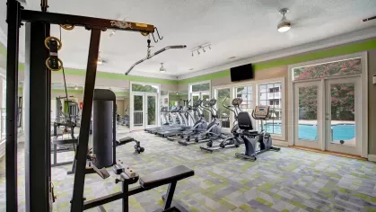 Another angle of the fitness center, highlighting advanced workout equipment and a view of the pool through large windows.
