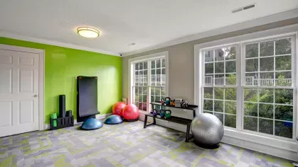 A bright fitness studio with exercise balls, kettlebells, and a yoga mat against a green accent wall.