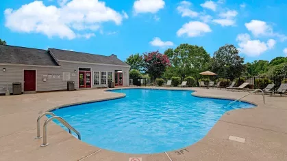 A relaxing pool area with a clubhouse nearby, surrounded by well-maintained landscaping.