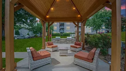 A cozy outdoor seating area under a wooden gazebo with soft lighting at 200 Braehill Apartments.