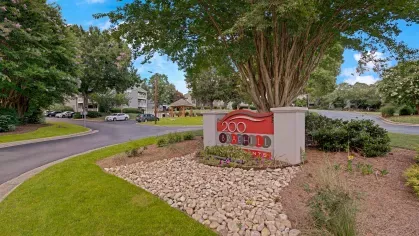 The main entrance and rental information center of 200 Braehill Apartments, featuring a red sign and well-maintained landscaping.
