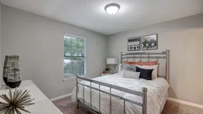 A bedroom with a cozy white bed, minimalist decor, and a window offering natural light.